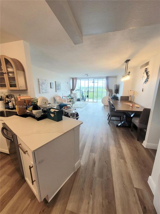 Open concept interior featuring wood-finish flooring, a kitchen island with stone countertops, arched upper cabinetry, and floor-to-ceiling glass sliding doors