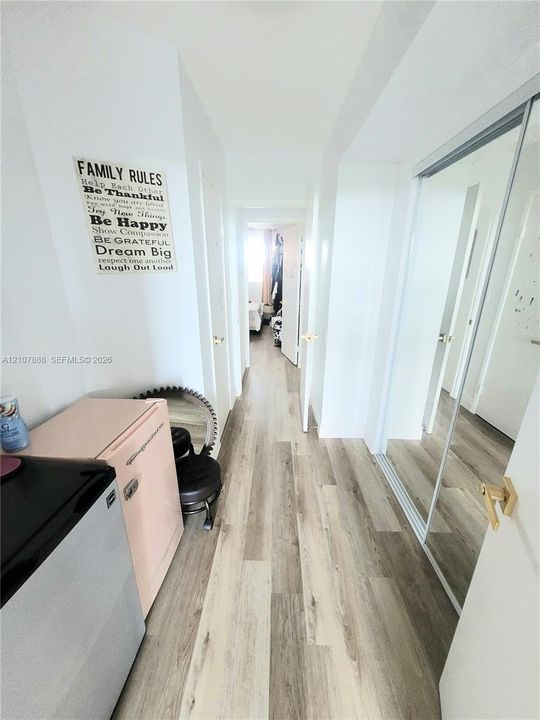 Hallway featuring wood-finish flooring and full-length mirrored closet doors