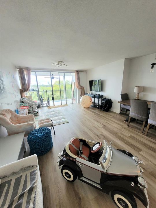 Open-concept floor plan featuring wood-finish flooring and floor-to-ceiling glass sliding doors providing access to a balcony