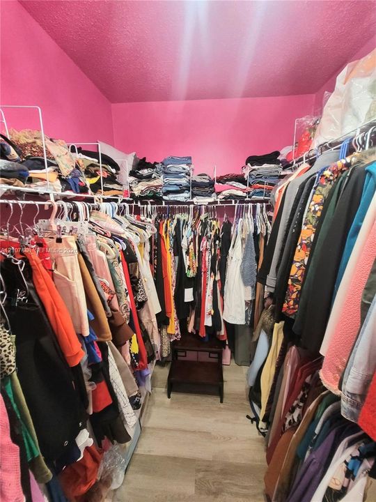 Walk-in closet featuring multi-tiered wire shelving and wood-finish flooring