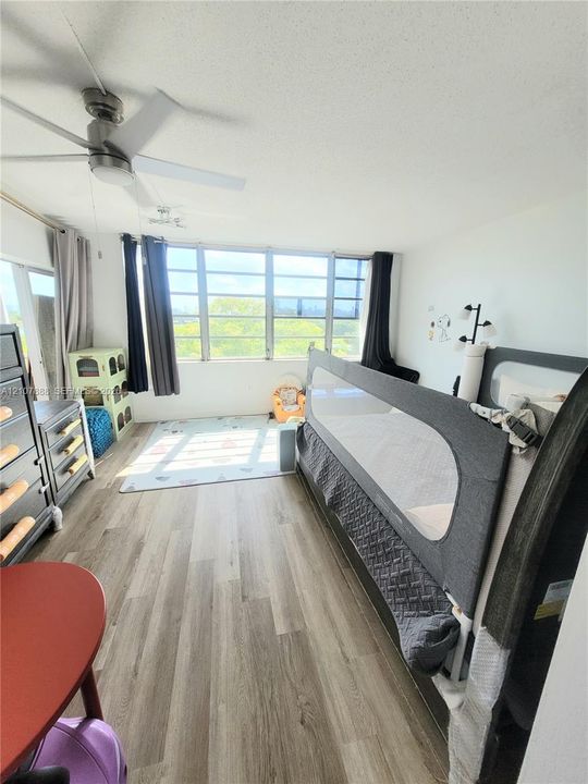 Wood-finish flooring, ceiling fan with integrated lighting, and expansive multi-pane windows providing natural light