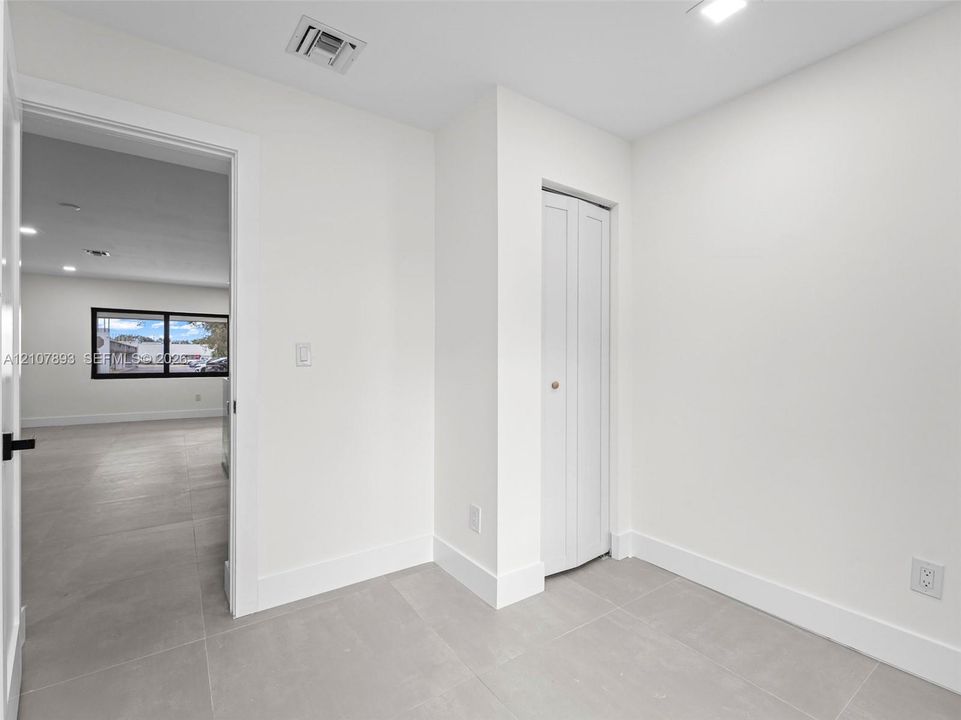 Large-format tile flooring, neutral wall palette, and bi-fold closet storage