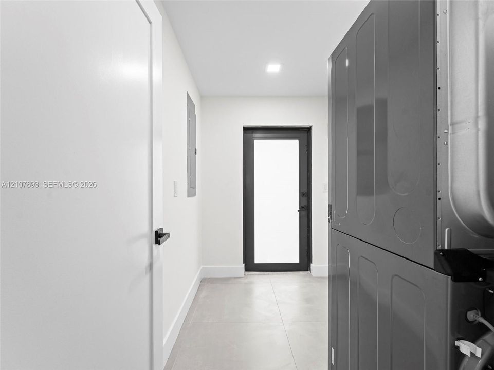 Neutral-toned tiled flooring, modern glass-panel exterior door, and matte black hardware