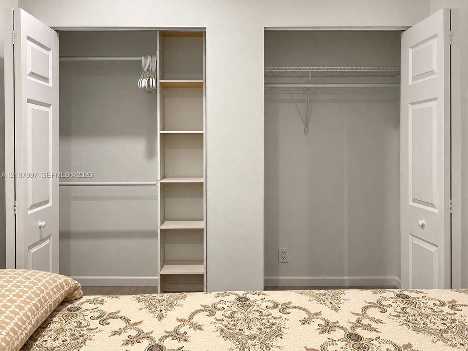 Dual reach-in closets featuring white paneled bifold doors, integrated shelving, and white wire rack systems