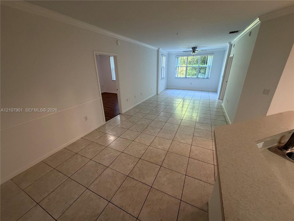 Ceramic tile flooring, crown molding, chair rail trim, ceiling fan, and solid-surface countertop with integrated sink