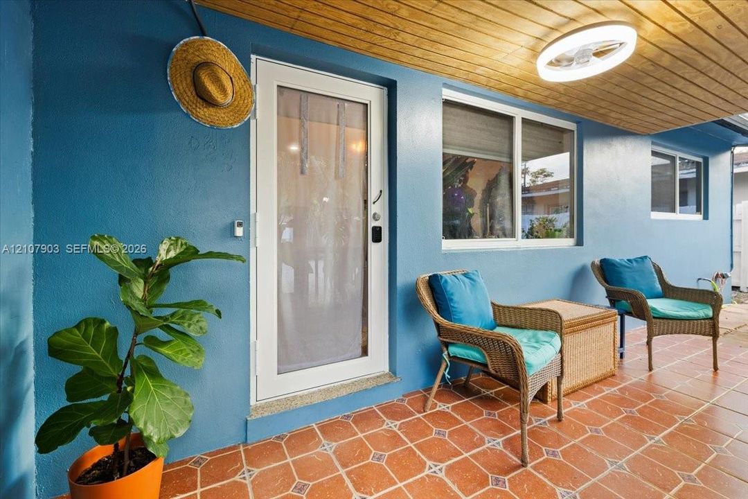 Covered patio featuring terra cotta tile flooring, wood-plank ceiling, and a full-light glass door