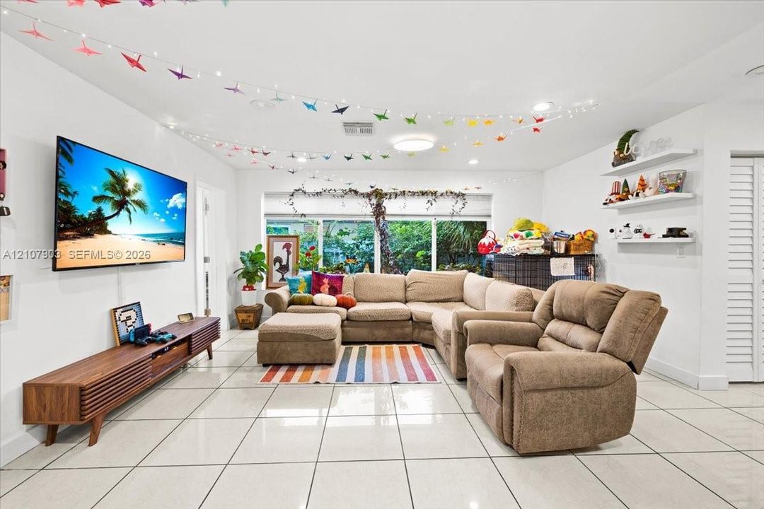 Living area featuring large-format tile flooring, recessed lighting, and built-in wall shelving