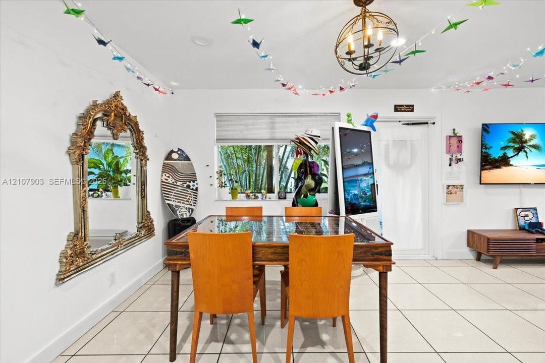Interior space featuring large-format tile flooring, a statement orb chandelier, and a wide window with integrated roller shade