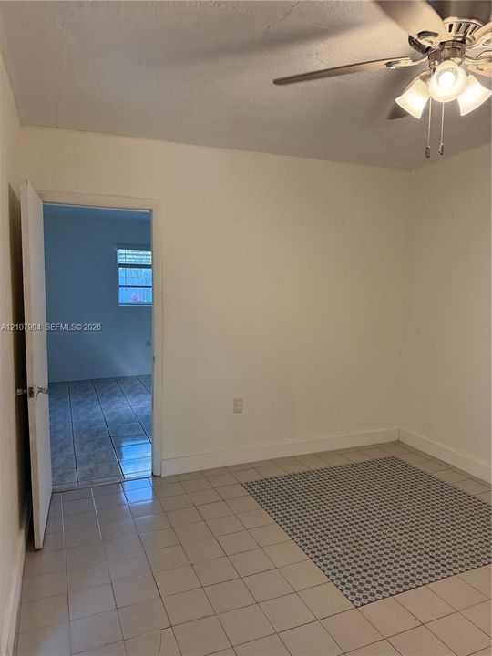 Interior space featuring neutral wall paint, tile flooring, and a ceiling-mounted light fixture with a fan
