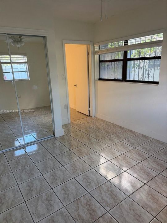 Room featuring large-format ceramic tile flooring, a mirrored sliding-door closet, and windows with multi-pane frames