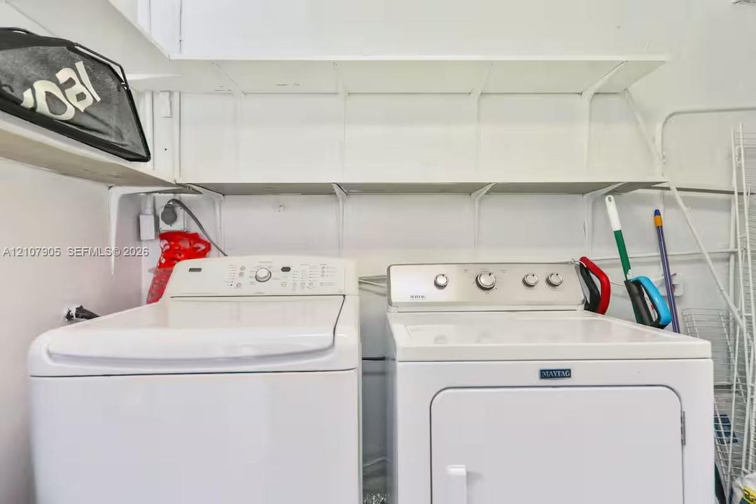 Laundry area featuring white top-load washer and dryer with extensive overhead built-in shelving