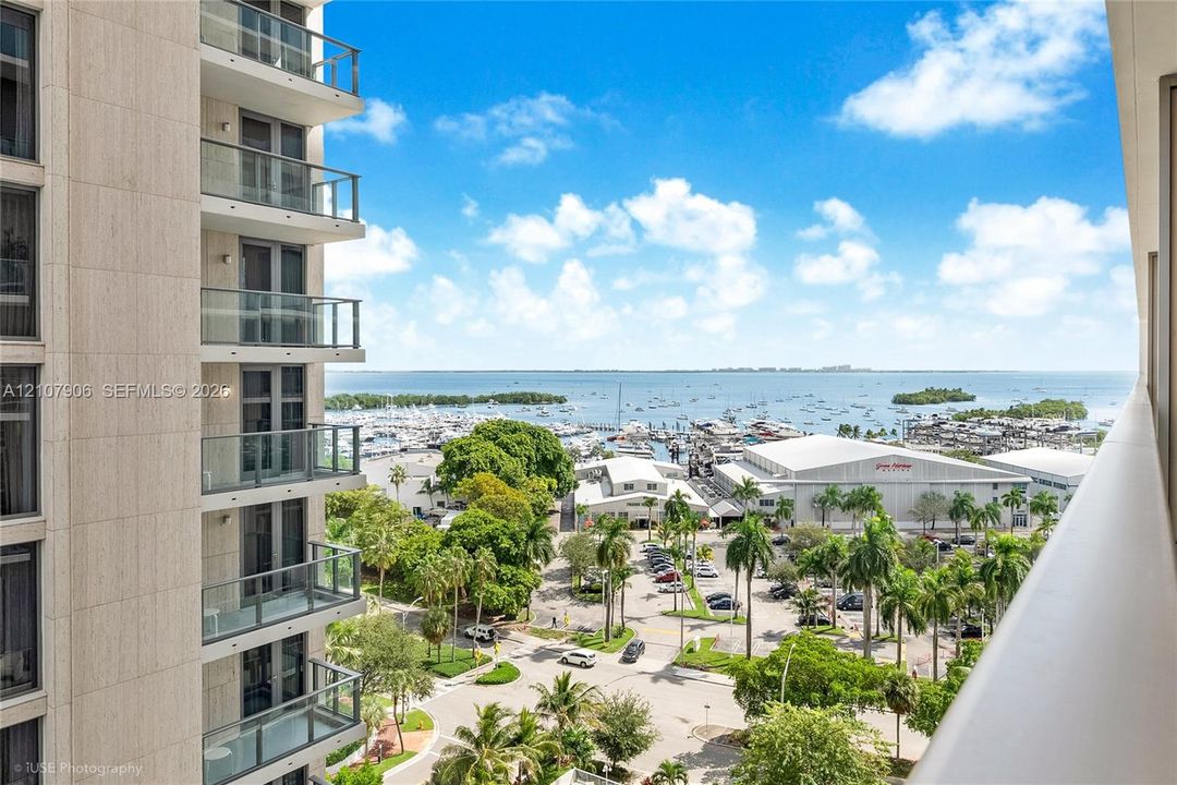 High-rise balcony featuring glass railings, floor-to-ceiling windows, and panoramic water and marina scenery