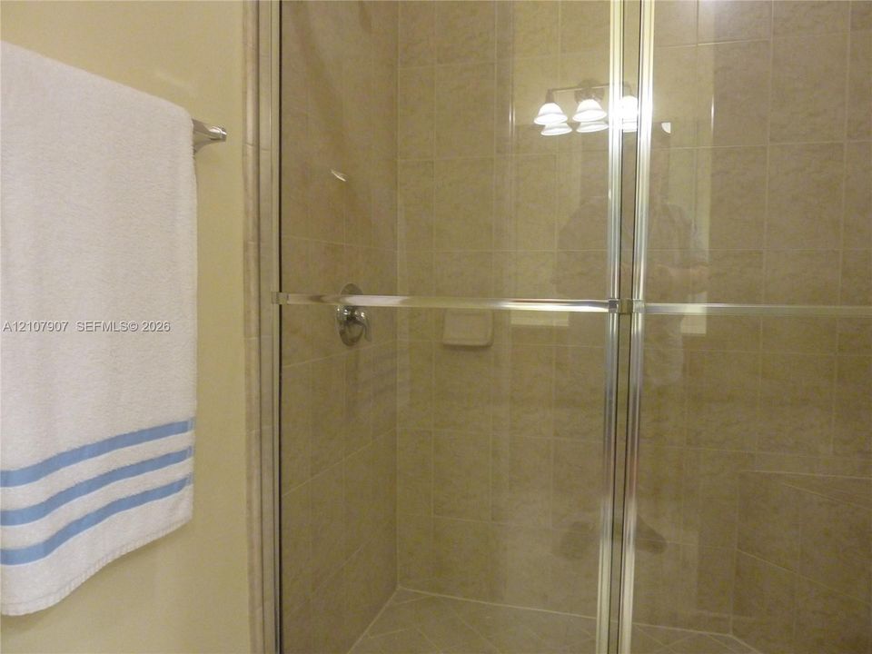 Shower enclosure featuring neutral-toned wall tile, a metal-framed glass door, and integrated tile soap niche