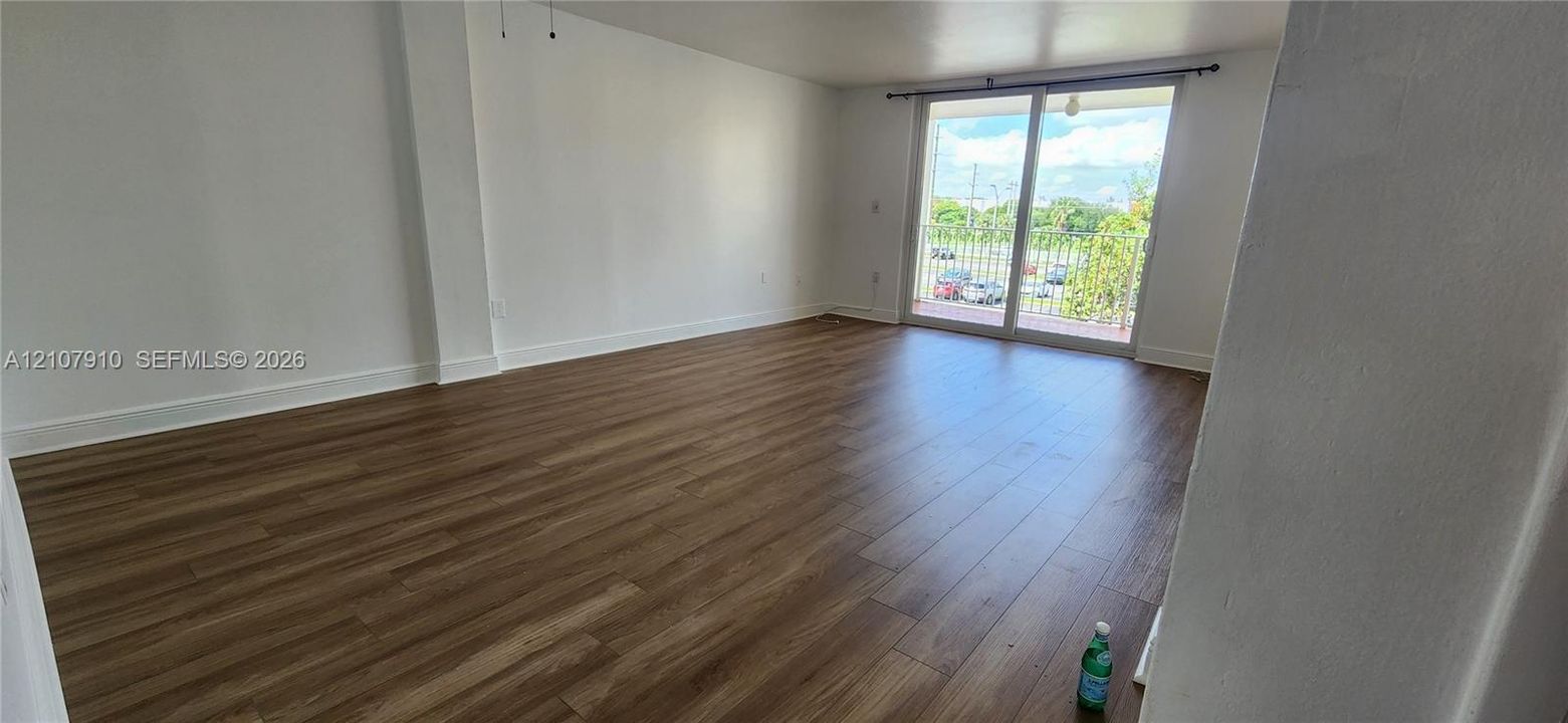 Open-concept interior featuring wood-finish flooring, neutral walls, and sliding glass doors providing outdoor access