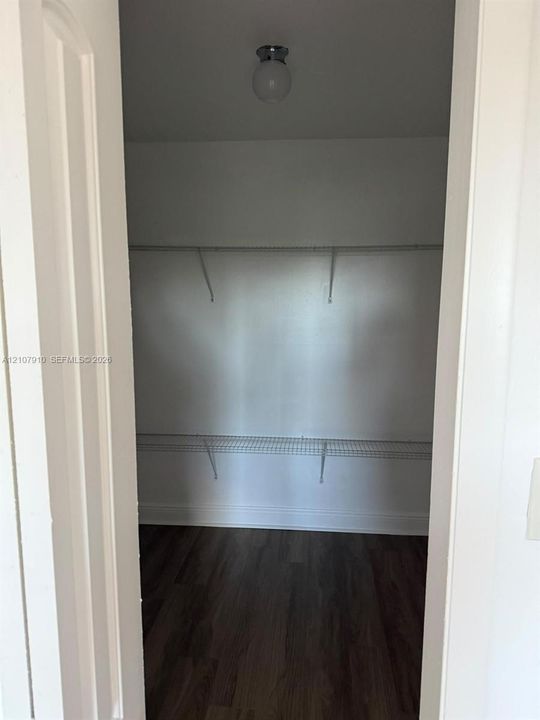 Storage space featuring wood-finish flooring, two-tier white wire shelving, and a dome-style flush mount ceiling light