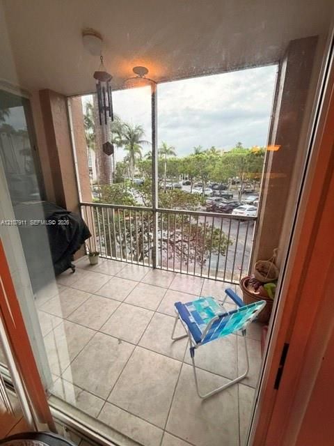 Screened-in balcony featuring large-format tile flooring, metal railing, and a ceiling-mounted light fixture
