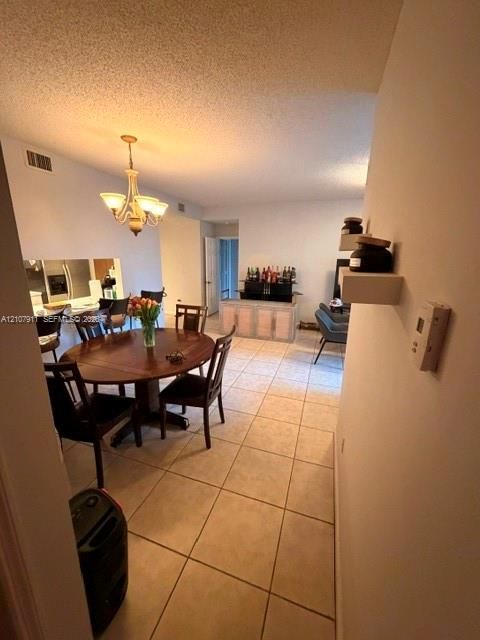 Ceramic tile flooring, neutral wall finishes, and a traditional five-arm chandelier