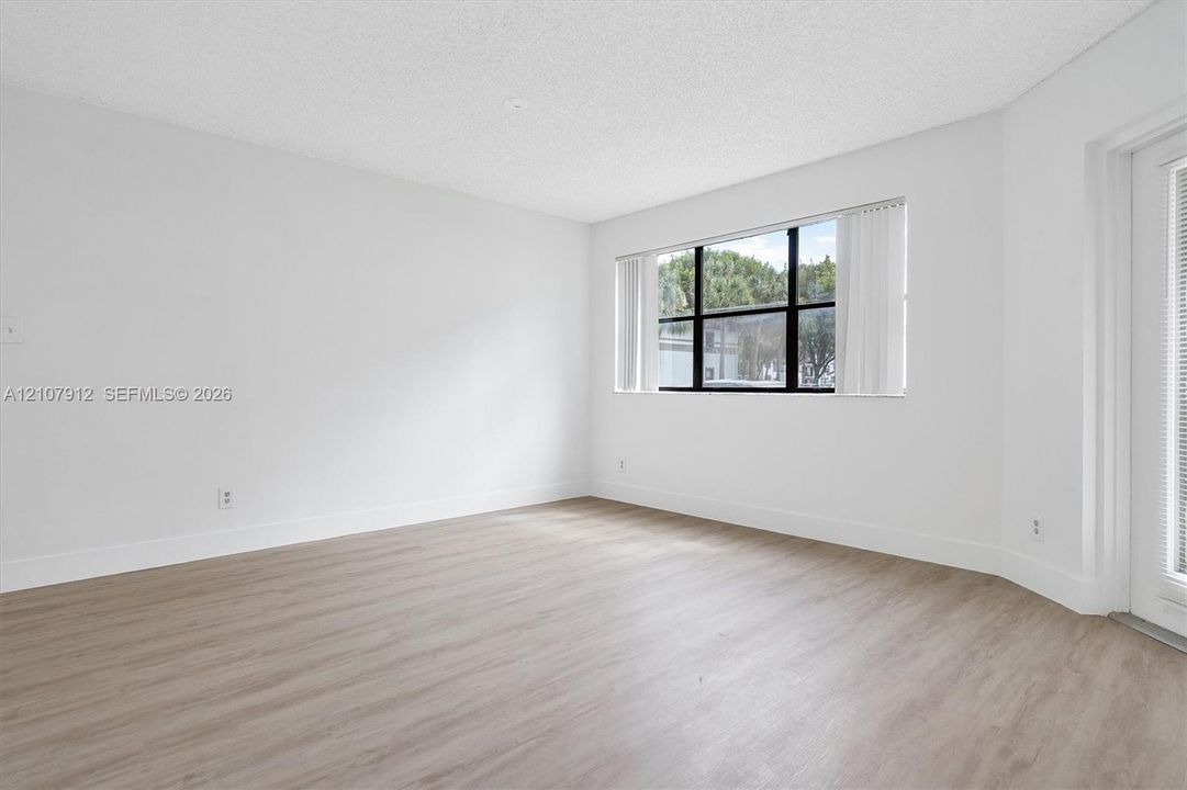 Interior space featuring wood-finish flooring, a large picture window with black frames, and a glass-paneled door