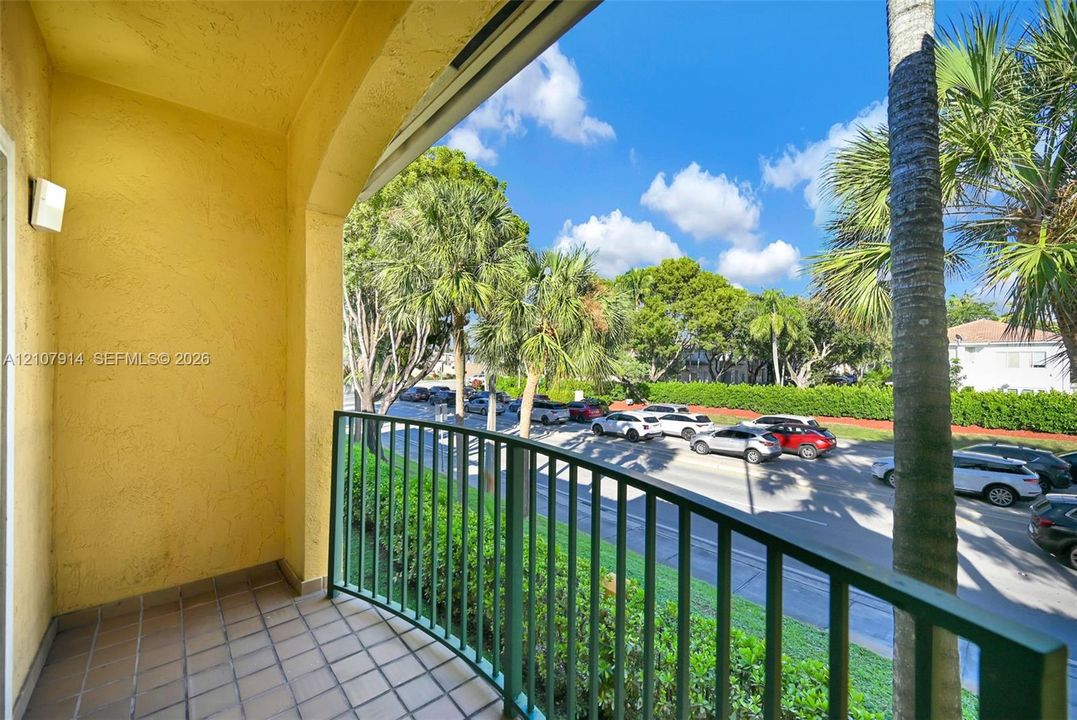 Covered balcony featuring tiled flooring, arched architecture, and metal railing