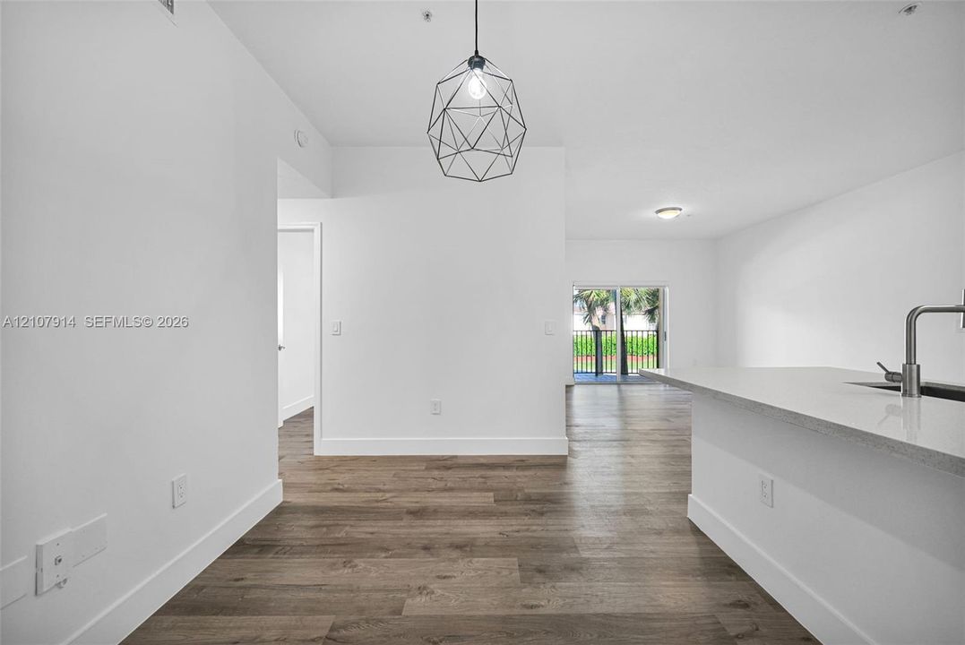 Wood-finish flooring throughout, geometric pendant lighting, stone-surface kitchen island, and metal-finish gooseneck faucet