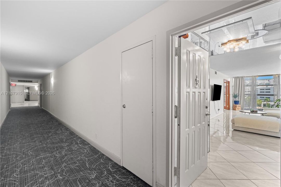 Entryway featuring a solid panel door, patterned wall-to-wall carpeting, and light-colored tile flooring
