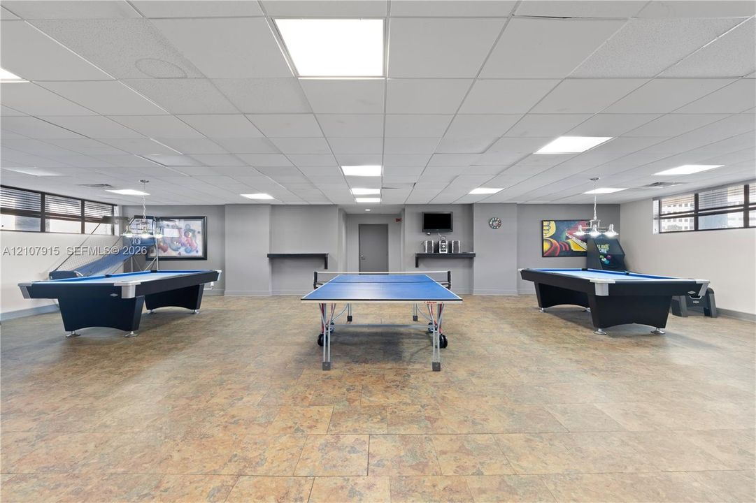 Spacious recreation area featuring a drop ceiling with recessed lighting, tile flooring, and perimeter windows