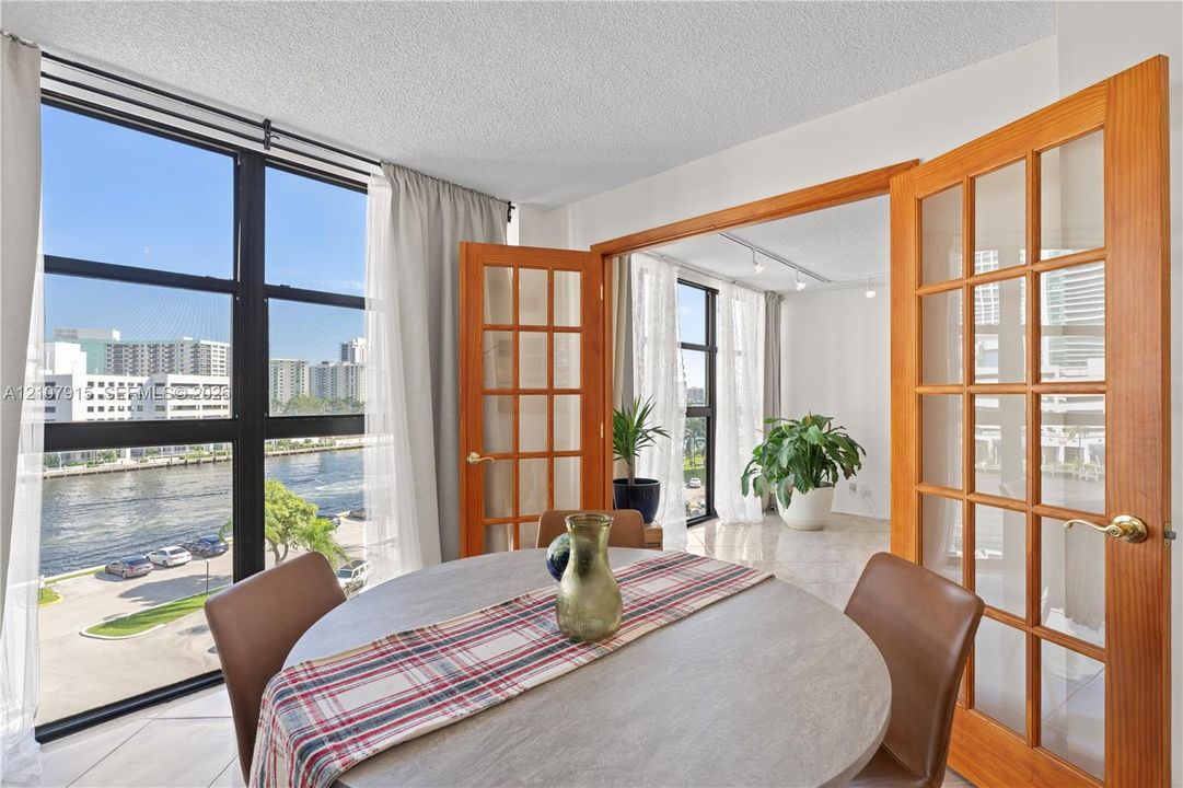 Floor-to-ceiling windows, wood-framed French doors, polished stone-finish flooring, and water-facing exposure