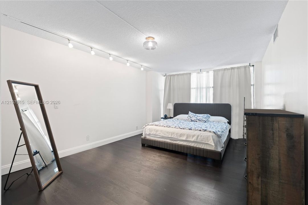 Interior space featuring dark wood-finish flooring, recessed ceiling lighting, track lighting, and expansive windows