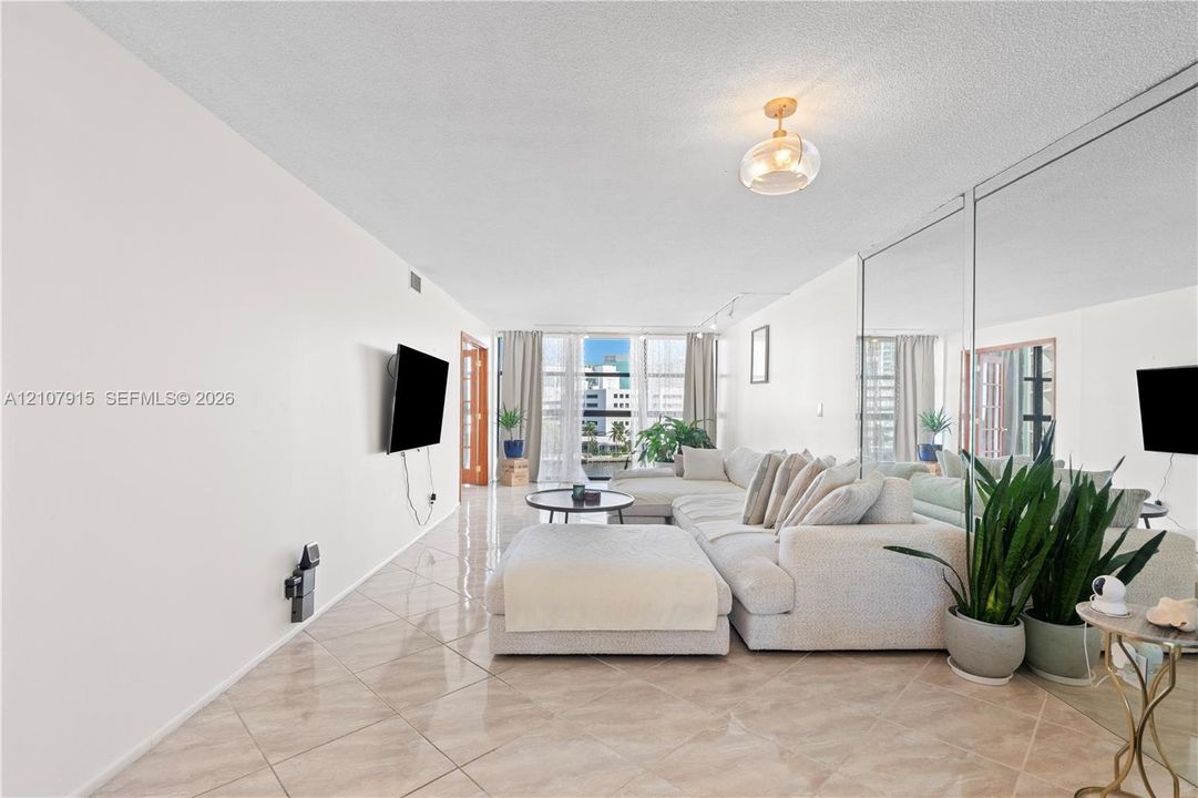 Floor-to-ceiling mirrored wall, polished tile flooring, glass-paneled entry door, and floor-to-ceiling windows with balcony access