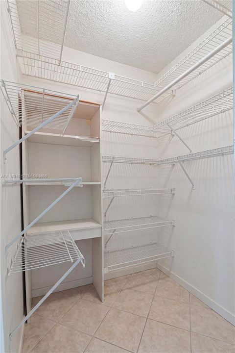 Storage area featuring built-in vertical shelving, multi-level wire rack organizers, and tile flooring