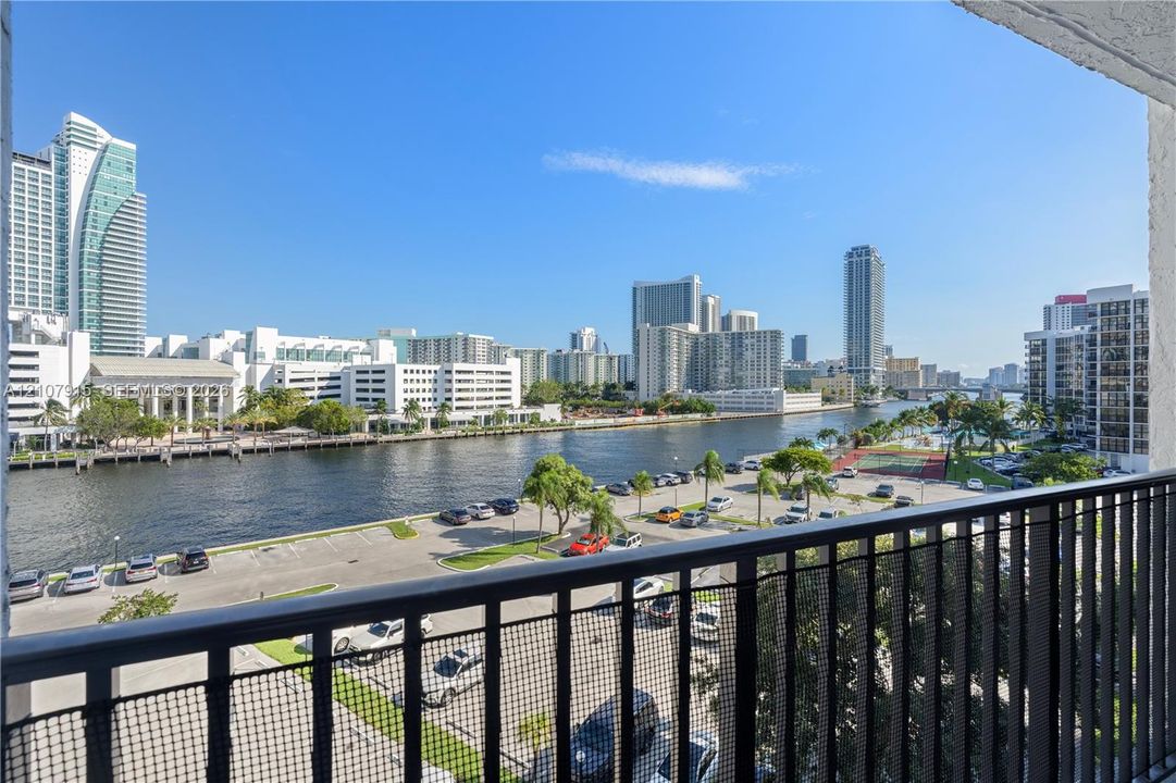Covered private balcony featuring black metal railings and direct water and urban skyline scenery