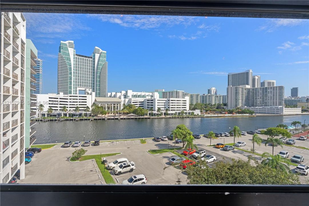 Waterfront perspective featuring high-rise urban architecture and paved parking area