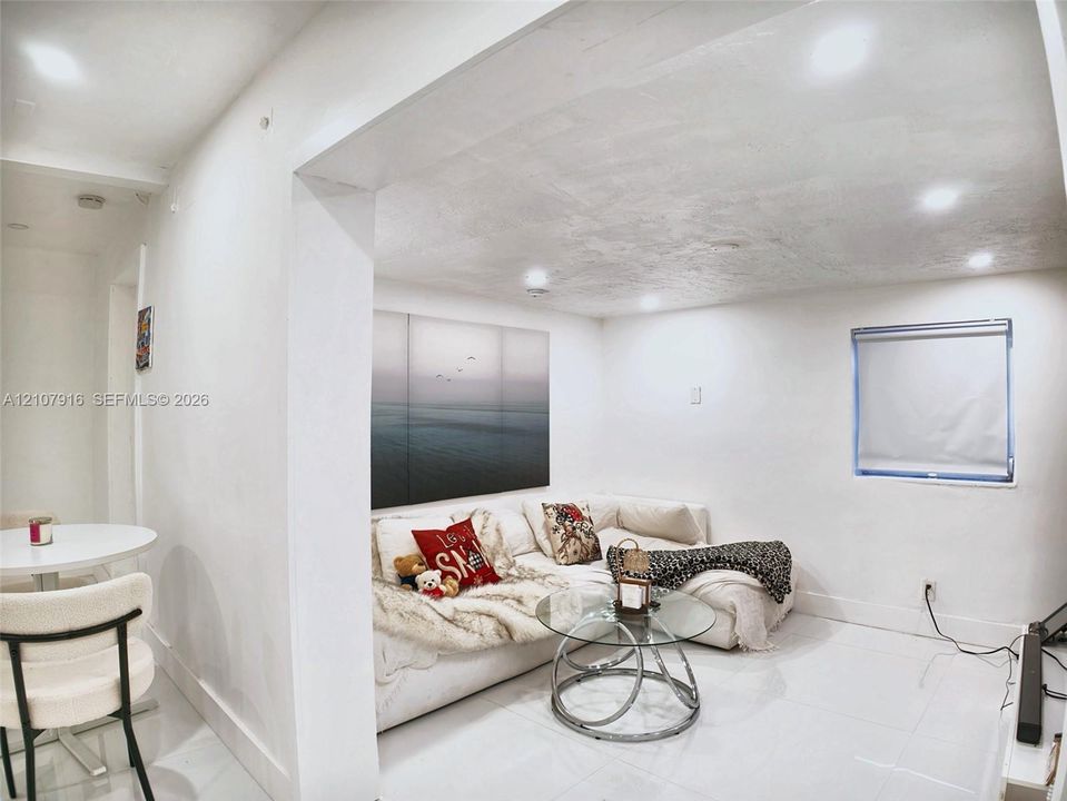 Interior space featuring recessed lighting, polished tile flooring, and a single-pane window with a roller shade