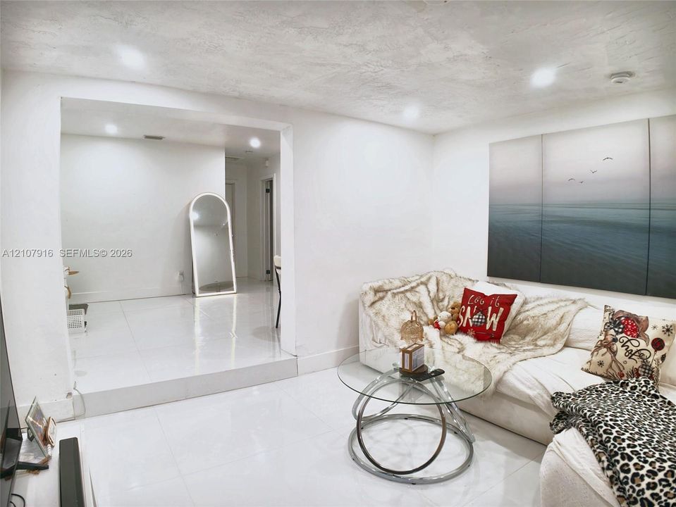 Interior space featuring polished white tile flooring, recessed ceiling lighting, and a raised floor level