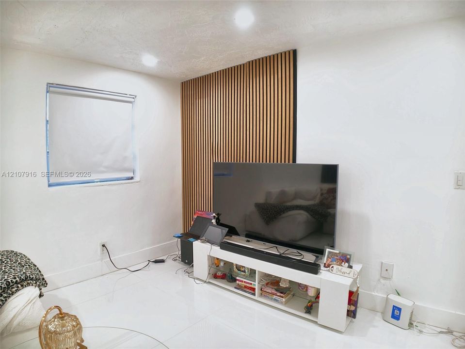 Vertical wood-slat accent wall featuring recessed lighting and glossy tile flooring
