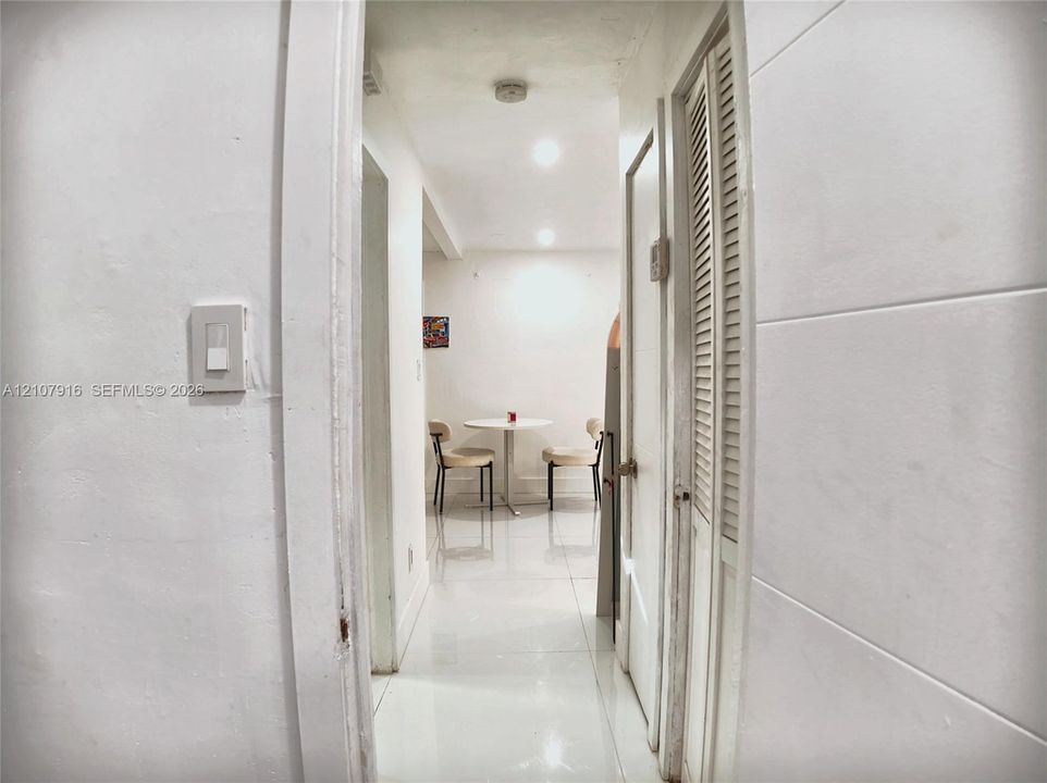 Hallway featuring white tile flooring, recessed ceiling lighting, and louvered bi-fold closet doors