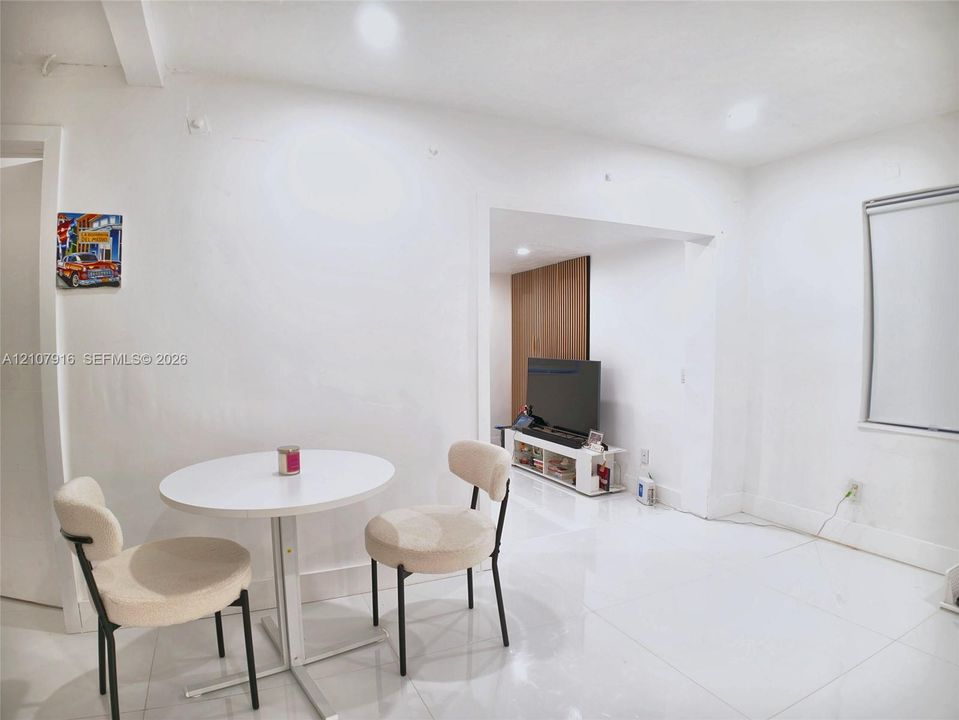 Bright interior featuring large-format tile flooring, crisp white walls, a recessed alcove, and floor-to-ceiling wood-finish cabinetry