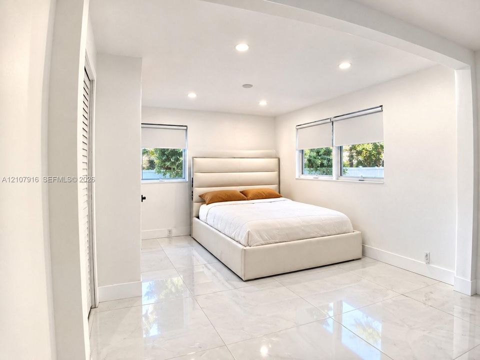 Polished stone-finish tile flooring, recessed ceiling lighting, and dual windows with roller shades