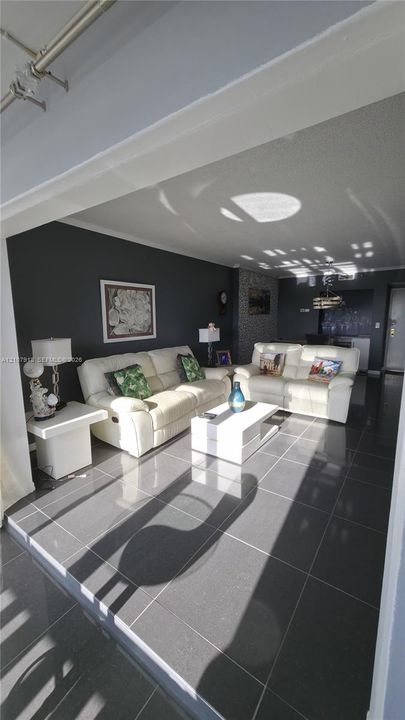 Large-format tile flooring, textured ceiling, and a prominent feature wall with masonry accents
