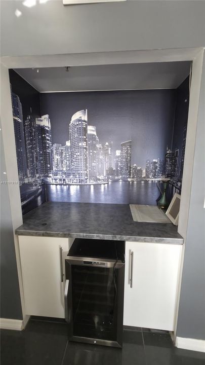 Built-in wet bar featuring white cabinetry, stone-finish countertop, and under-counter beverage refrigerator