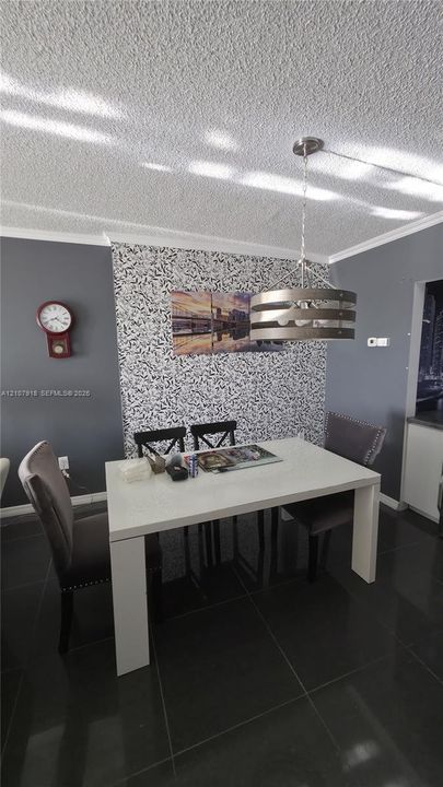 Textured ceiling, accent wall with patterned finish, and industrial-style metal drum pendant light over large-format tile flooring
