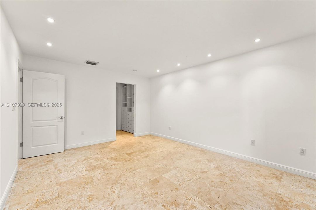Neutral-toned stone tile flooring, recessed ceiling lighting, and custom built-in cabinetry