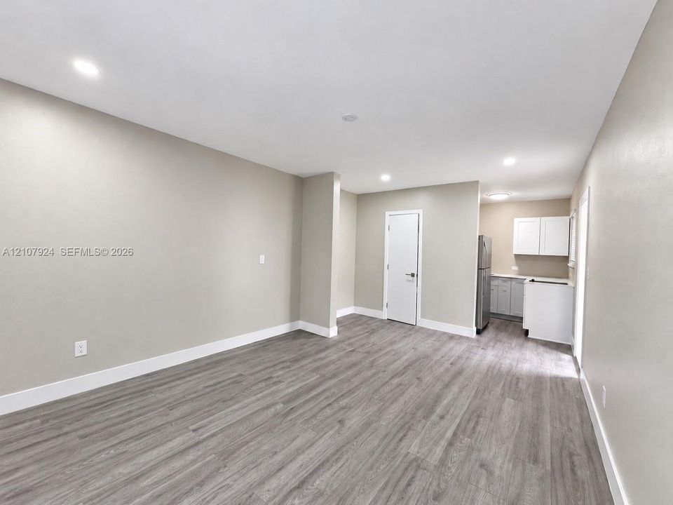 Neutral-toned interior featuring wood-finish flooring, recessed lighting, and a kitchenette equipped with two-tone cabinetry and stainless steel appliances