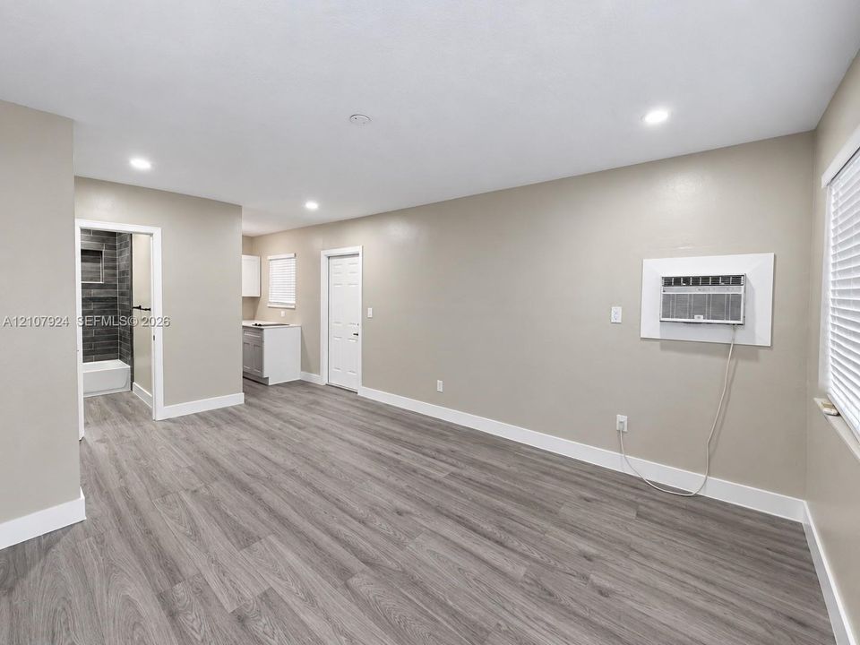 Open interior space featuring wood-finish flooring, recessed lighting, and wall-mounted air conditioning unit
