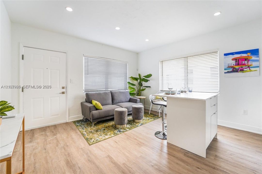 Interior featuring wood-finish flooring, recessed lighting, and a white kitchen island with solid surface countertop