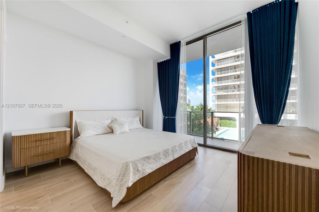Floor-to-ceiling windows featuring access to a private balcony, wood-finish flooring, and neutral wall tones