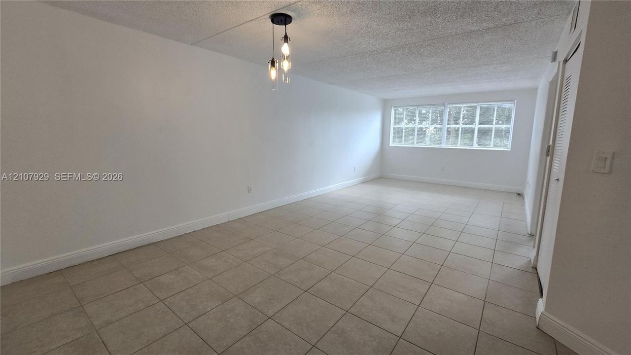 Neutral-toned ceramic tile flooring, three-light pendant fixture with glass shades, and large multi-pane windows