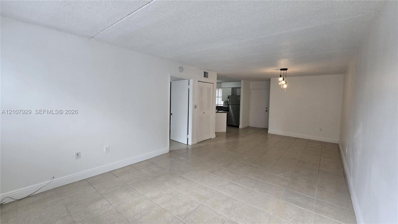 Open-concept interior featuring neutral tile flooring, textured ceiling, and a multi-pendant light fixture