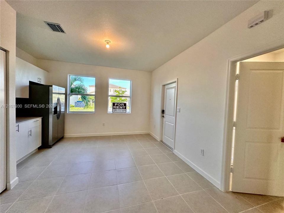 Kitchen featuring matte white cabinetry, stainless steel side-by-side refrigerator, neutral ceramic tile flooring, and dual picture windows