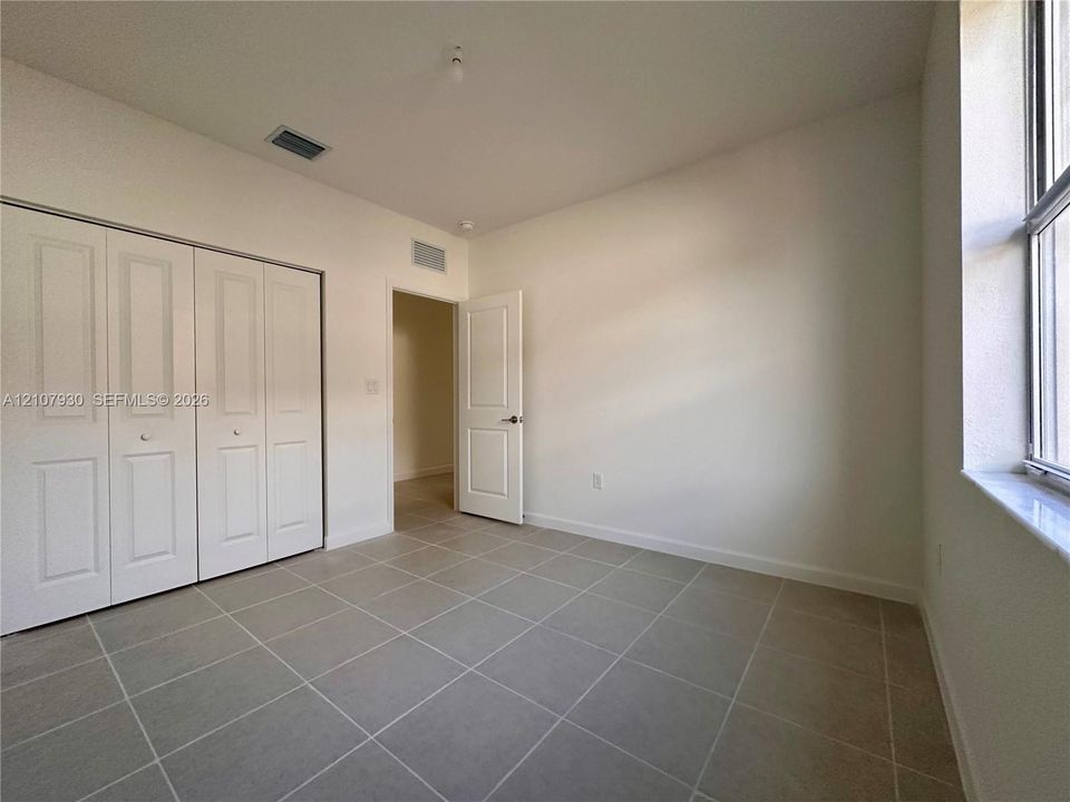 Neutral-toned ceramic tile flooring, built-in bifold closet doors, and a multi-panel interior door